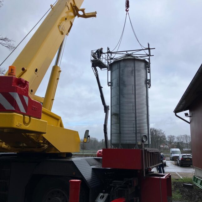 Zu sehen ist die Montage eines Silos mit einem Kran auf spezielle Anschlagpunkte.